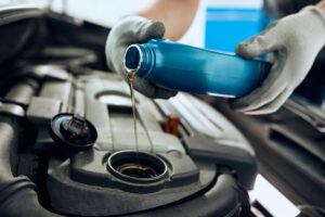 Close Up Of Repairman Changing Engine Oil While Working At Car Workshop.